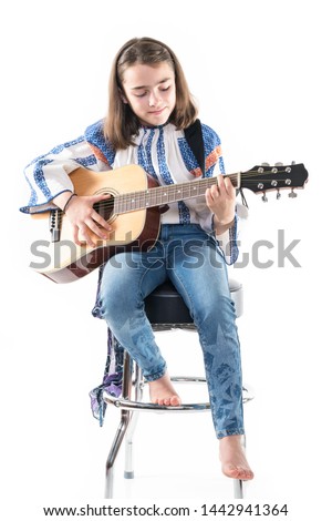 Preteen girl playing her guitar isolated on a white background.