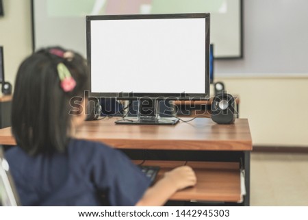 Back view of preteen girl or children studying with computer is working on a new project on desktop computer with blank copy space screen for your advertising text message