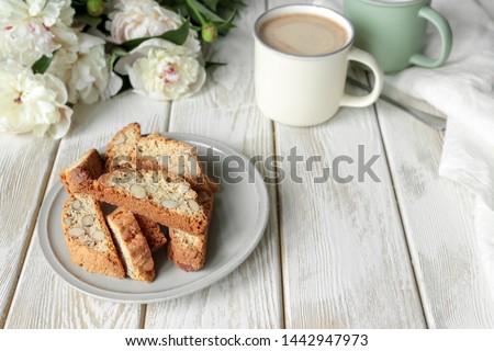 traditional Italian biscotti cookies, coffee milk, peonies on a wooden table