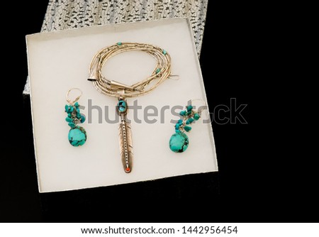 A gift box opened to display a Native American turquoise,coral and silver feather pendant and earrings.