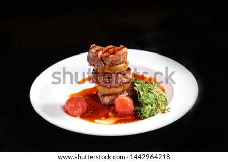 Beef filet mignon with vegetables on a white plate. Macro photo on black background. Grilled meat and vegetables.