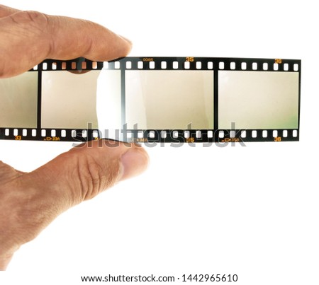 male hand holding 35mm filmstrip with empty frames or film cells, photo placeholder for your content, fingers holding film material