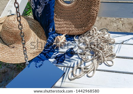 Sunglasses on a white bench with a magazine, rope, hat and bag. Beach holidays, travel, resort.