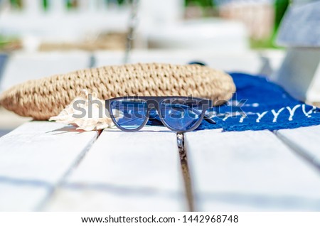 Sunglasses on a white bench on the beach magazine, bag, blue fabric. Beach holidays, travel, resort, eye protection.