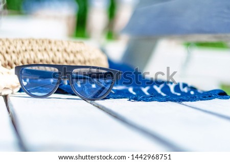 Sunglasses on a white bench on the beach magazine, bag, blue fabric. Beach holidays, travel, resort, eye protection.