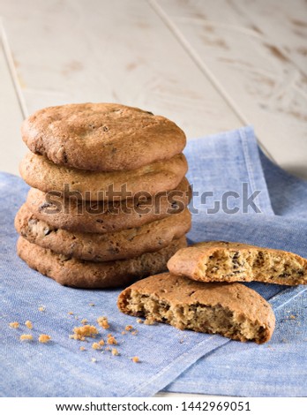 Chocolate chips cookies under a blue napkin on a white wooden table