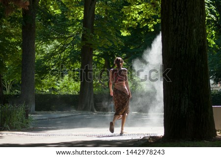 Portrait of woman walking in urban park in sprayer on back view 
