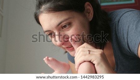 Mother interacting with newborn baby feet and foot holding and kissing showing love affection and baby care