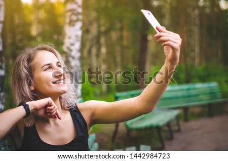 The girl takes a selfie. Photo for social networks. Internet. Blonde woman in sports clothes. Emotions. Photo.