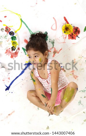 Good young girl draws with paints on a white