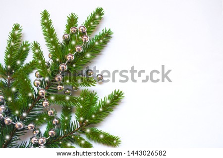 White minimalistic background with snowy branch of fir-tree with garland. Place for text. Christmas concept