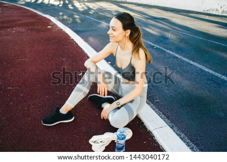 Young woman with a bottle of water after Jogging outdoors in Singapore. She is wearing grey top and a light sports leggings