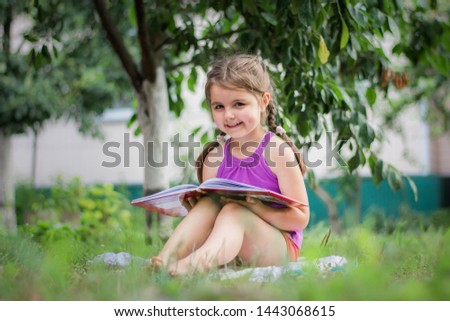 little girl reading a book in the garden