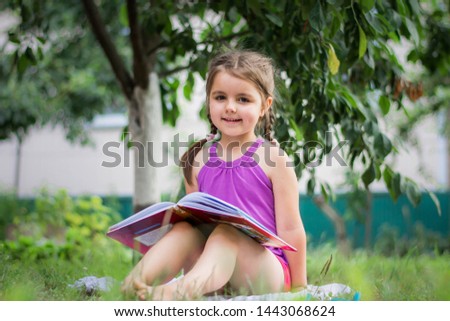 little girl reading a book in the garden