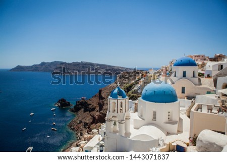 Oia town on Santorini island, Greece. View of traditional white houses and churches with blue domes over the Caldera, Aegean sea