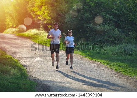 Young people jogging and exercising in nature, in morning sunrise warm light Royalty-Free Stock Photo #1443099104