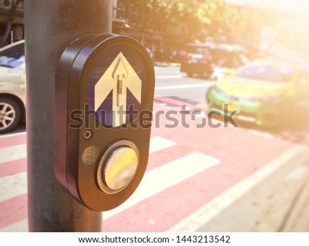 focus on push button traffic light for across the road with flare light and blurred outdoor background, close up shot