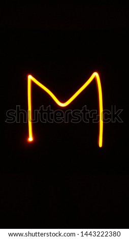 Letter M written by light in the dark with long shutter speed
