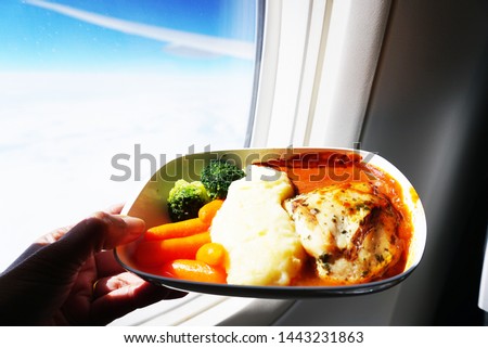 
Chicken steak served with mashed potatoes, vegetables, carrots, borkery served on the plane. Is a picture of a close-up shot in the plane window