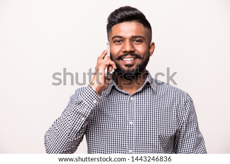 Young happy Indian man talking on mobile phone isolated against white background