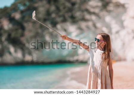 Happy little girl taking selfie at tropical beach on exotic island during summer vacation