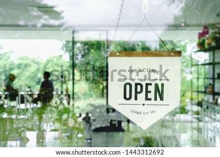Welcome and open sign hanging on window glass in coffee shop.