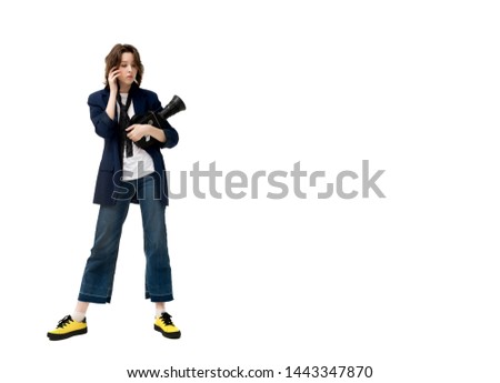 Beautiful brunette girl in a jacket and jeans on a white background with an old vintage professional 16 mm movie camera, isolated