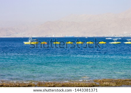 yellow attraction boats near shoreline beach in the most south Israeli city Eilat  on Red sea waterfront, summer vacation entertainment concept photography 