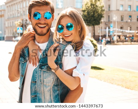 Smiling beautiful girl and her handsome boyfriend. Woman in casual summer dress and man in jeans clothes. Happy cheerful family. Female having fun on the street background.Hugging couple in sunglasses