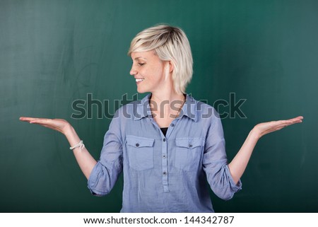Blond woman holding out her empty palms against chalkboard