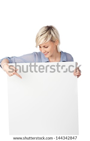 Young blond woman pointing at white sign against white background