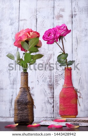 Pink and orange roses in vintage bottles against the white wooden wall