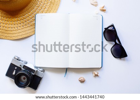 Flat lay design of travel concept with camera, notebook, hat, shells on white background
