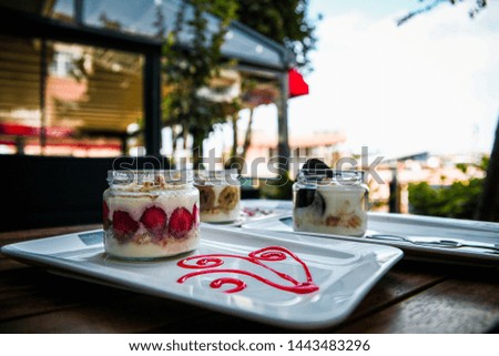 Layered dessert or Magnolia with cocoa biscuit and pudding in the glass cup. here are strawberry banana and raspberry on the desserts.