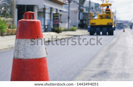 Close up the old traffic cone with blurred background of road roller working on the street in the city, construction concept 