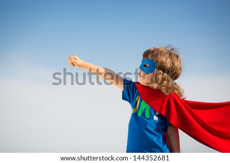 Superhero kid against blue sky background. Girl power concept Royalty-Free Stock Photo #144352681