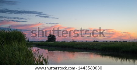 Panorama of colorful distant clouds over the scenic dutch countryside