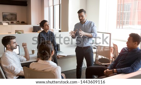 Serious business man team leader coach mentor talk to diverse business people in office explain strategy at corporate group meeting, multiethnic staff listen to boss instruct interns at briefing Royalty-Free Stock Photo #1443609116