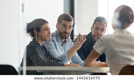 Serious male boss team leader hr recruiter talking to businesswoman client applicant at job interview or corporate briefing sit at table, businessman executive negotiating at diverse group meeting Royalty-Free Stock Photo #1443616970