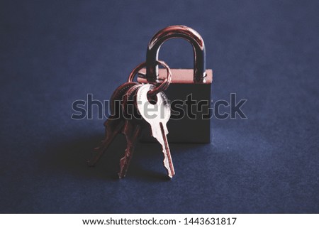 Silver metal check lock and three keys on dark blue background. Modern padlock concept. 