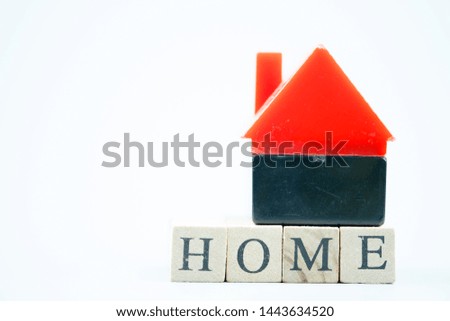 Red toy home put on wooden block with HOME on white background