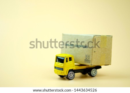 Miniature cardboard boxes on yellow toy truck carries. Concept of online orders. Delivery of the order from the online store