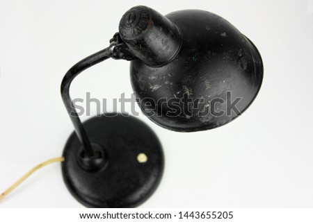 an antique black table lamp from the 20s bauhaus era standing on an old desk worn out and damaged isolated on white background very rare in original condition design icon