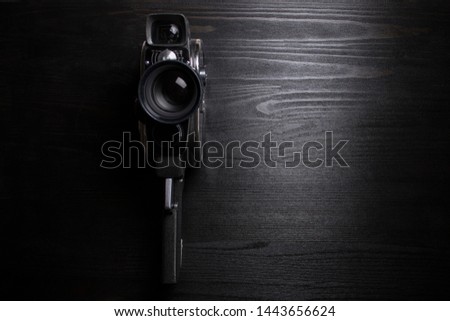 Vintage video camera on a black wooden board. Background, wallpaper, copy space.