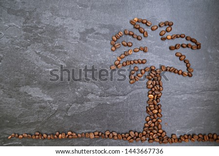 On a dark marble surface are coffee beans in the shape of a palm, next to it is space for text or other elements - concept for coffee on vacation or coffee as a relaxation on hot summer days