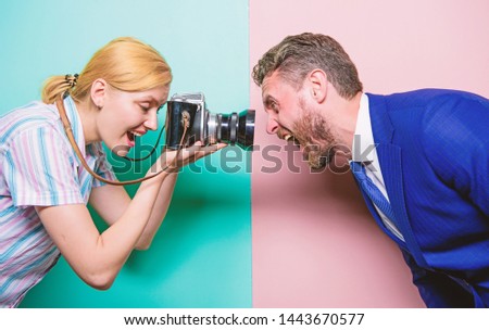 Capturing his face expression. Pretty woman using professional camera. Photographer shooting male model in studio. Businessman posing in front of female photographer. Fashion shooting in photo studio.