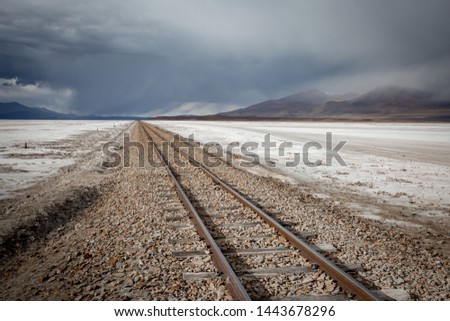 Lonely railroad tracks crossing the Bolivian desert during snowy, stormy weather in South America 