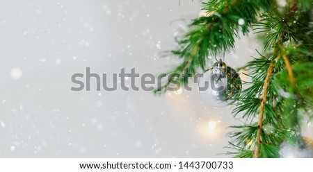 New Year's silver shiny ball hanging on a fir branch. Lights and garlands on a gray snow background. Christmas and happy new year concept, space for text for your design. Wallpaper.