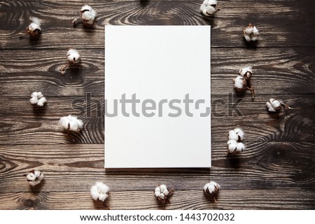 Artistic canvas and cotton plant. Natural white blank cotton canvas on brown wooden background. Top view. Mockup