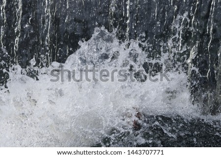 Spray clear water from a small waterfall. Background and texture